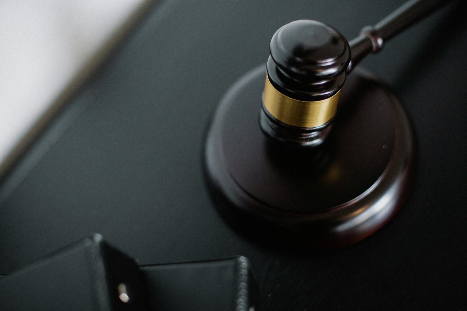 pexels-photo-5668481-5668481 Close-up of a wooden judge's gavel on a black desk, symbolizing justice and law.